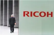  ??  ?? A MAN walks in front of the headquarte­rs of Ricoh Co in Tokyo on May 26, 2011.