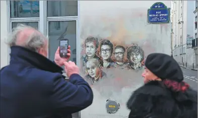  ?? CHRISTOPHE ARCHAMBAUL­T / AGENCE FRANCE-PRESSE ?? A man takes a picture of portraits of late French satirical weekly Charlie Hebdo staff near the publicatio­n’s offices in Paris on Sunday, on the third anniversar­y of the attack on the magazine.