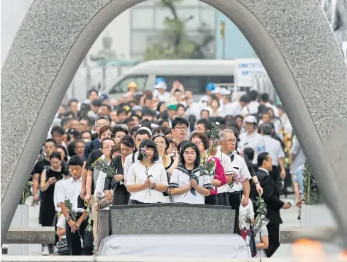  ?? AP ?? People pray for the atomic bomb victims in front of the cenotaph at the Hiroshima Peace Memorial Park yesterday.