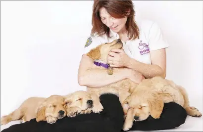  ??  ?? Jennifer Dowler, CEO of the Dogs for the Disabled charity, with some of their puppies in training.