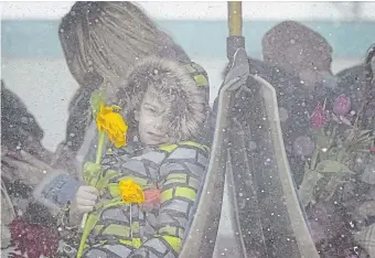  ?? ANDREEA ALEXANDRU THE ASSOCIATED PRESS ?? A refugee child fleeing the conflict from neighbouri­ng Ukraine holds flowers, given out to celebrate Internatio­nal Women’s Day, as he sits on a bus, at the RomanianUk­rainian border, in Siret, Romania, on Tuesday.