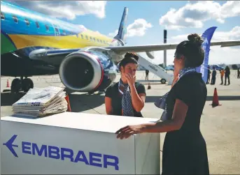  ?? BLOOMBERG VIA GETTY IMAGES ?? Embraer SA employees manning the company's booth during the Internatio­nal Brazil Air Show at Rio Galeao Internatio­nal Airport in Rio de Janeiro, Brazil, on April 1, 2017.