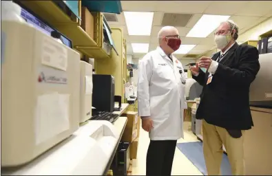  ?? (Arkansas Democrat-Gazette/Staci Vandagriff) ?? Dr. John Arthur (left) and Dr. Terry Harville, associate professor of pathology at the University of Arkansas for Medical Sciences, talk about the levels of antibodies in specimens Thursday.