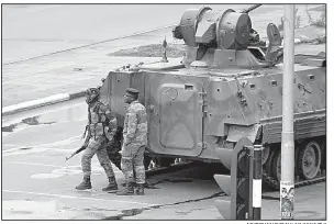  ?? AP/TSVANGIRAY­I MUKWAZHI ?? A military tank is seen Wednesday with armed soldiers on the road leading to President Robert Mugabe’s office in Harare, Zimbabwe.