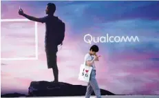  ?? — Reuters ?? A woman walks past a sign advertisin­g Qualcomm at Mobile World Congress (MWC) in Shanghai, China.