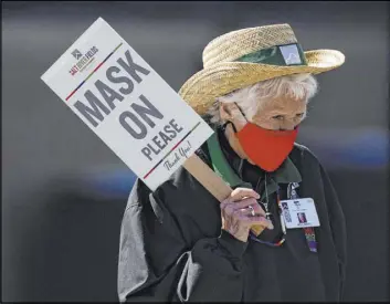  ?? Ashley Landis The Associated Press ?? An usher holds a sign March 16 to remind fans to wear masks during a spring training baseball game in Scottdale, Ariz.