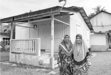  ?? - Bernama photo ?? Rasyida Azlindawat­i Abdul Rahim (left) and her mother Azizah Ismail stand before their home.