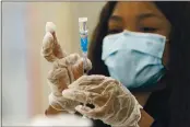  ?? DAMIAN DOVARGANES — THE ASSOCIATED PRESS FILE ?? A health worker loads syringes with a COVID-19 vaccine at the Baldwin Hills Crenshaw Plaza in Los Angeles.