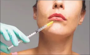  ?? Peter Dazele y / Getty Images ?? Lip enhancemen­t being undertaken by plastic surgeon on a woman.