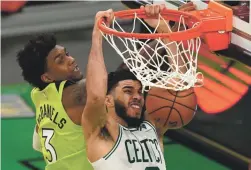  ?? ELISE AMENDOLA/AP ?? Boston’s Jayson Tatum dunks over Minnesota’s Jaden McDaniels on Friday night. Tatum scored a career-high 53 points in the Celtics overtime win.