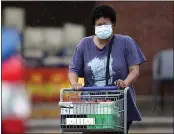  ?? DAVID J. PHILLIP — THE ASSOCIATED PRESS ?? A shopper wears a mask as she pushes her grocery cart in the rain Thursday in Houston.