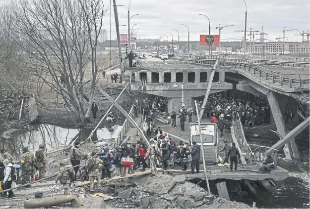  ?? ?? With Russian forces nearing Kyiv ten days after Russia launched a military invasion on Ukraine in February 2022, refugees flee across a damaged bridge in the city of Irpin, northwest of the capital amid heavy shelling and bombing