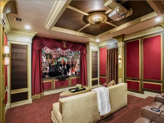  ?? Provided by John McClain Design/Zeke Ruelas via Associated Press ?? A home theater bedecked with red velvet on the wooden wall panels. A champagne-hued velvet is on the big couch in foreground. For an Orlando, Florida project, designer John McClain and his client wanted to evoke an Art Deco aesthetic, yet still design a functional state-of-the-art home theater.