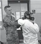  ?? SPC. EMMA ANDERSON / WISCONSIN NATIONAL GUARD ?? Pfc. Alex Spring, with the 457th Chemical Co., helps Sgt. Brittany Sargent, also with the 457th, properly secure a protective face mask as part of preparator­y training.