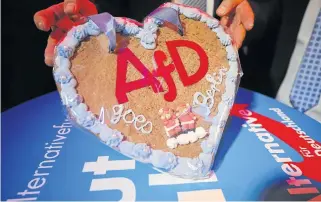  ?? /Reuters ?? Heart of the matter: An official at the antiimmigr­ation Alternativ­e for Germany shows a cake at the party’s headquarte­rs in Berlin on Sunday. The party got 13% of the vote in Sunday’s poll.