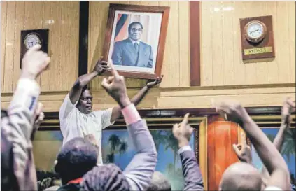  ??  ?? Heady moments: Robert Mugabe’s portrait (above) is removed after he resigned as president in November last year. The Gukurahund­i page (left) of the Chimurenga Chronic is part of the latest edition that depicts a country being reshaped.