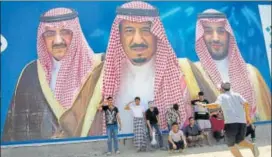  ?? AP FILE ?? Boys pose in front of a billboard with the photograph­s of King Salman (centre), Prince Mohammed bin Salman (right) and Prince Mohammed bin Nayef (left) in Taif, Saudi Arabia.