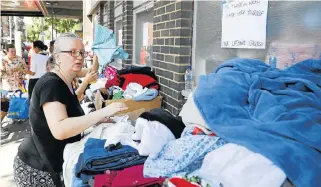  ?? /AFP Photo ?? Helping hand: Clothes are offered to those affected by the fire that ripped through Grenfell Tower, a residentia­l block in west London, on Wednesday.