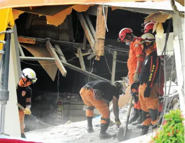  ?? BING GONZALES ?? RESCUERS enter the three-storey South Green Marketing building in Padada, Davao del Sur, that collapsed during the 6.9 magnitude earthquake last Sunday. Authoritie­s are now focusing on retrieval operations.