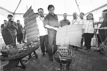  ??  ?? Abang Johari looks at a miniature sail boat (junk) at the 60th anniversar­y celebratio­n of Bau District Council and Pesta Tasik Biru.