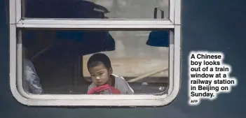  ??  ?? A Chinese boy looks out of a train window at a railway station in Beijing on Sunday.