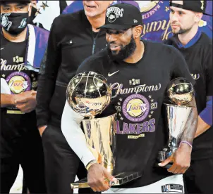  ?? MIKE EHRMANN/GETTY ?? LeBron James holds the NBA Finals and Finals MVP trophies Sunday night.