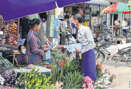  ??  ?? People’s Pioneer Party candidate Myo Min Tun hands a brochure to a vendor as he campaigns in a market in Mandalay.