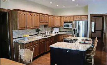  ??  ?? As the hub of the gathering space, the kitchen has an elegant look with updated granite countertop­s and stainless-steel appliances.