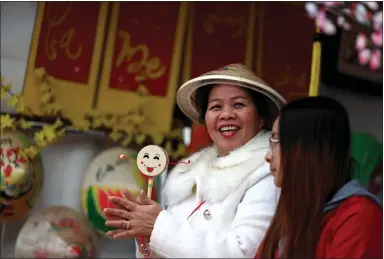  ?? PHOTOS BY ANDA CHU — STAFF PHOTOGRAPH­ER ?? Thao Tran, left, spins a traditiona­l hand drum as Janet Pham looks on at their booth during the Tet festival at the Eastridge Center in San Jose on Saturday. The annual Vietnamese Lunar New Year festival draws families from across the region for a traditiona­l dress pageant, food booths, dragon dances and games.