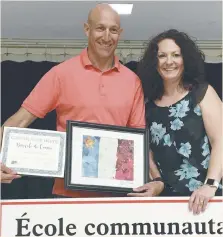  ??  ?? André Roy, enseignant en éducation physique, reçoit son certificat de mérite comme bénévole de l’année de Kristie Roy, directrice de l’École communauta­ire Le Domaine Étudiant.