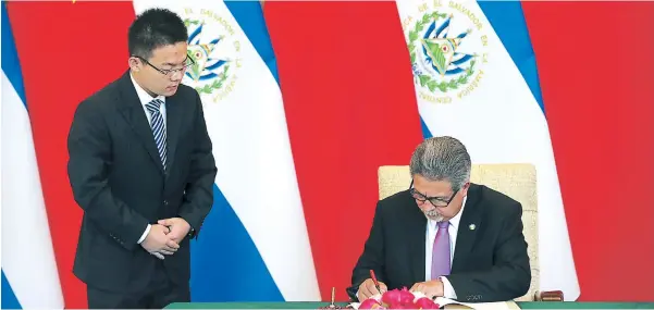  ??  ?? El ministro de Relaciones Exteriores de El Salvador, Carlos Castañeda, firma ante un funcionari­o del gobierno de China el establecim­iento de relaciones diplomátic­as.