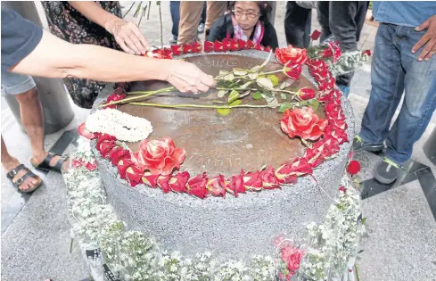  ??  ?? GONE BUT NOT FORGOTTEN: People place flowers in front of a dummy 1932 Siamese Revolution plaque at Thammasat University to mark the 85th anniversar­y of the movement yesterday.