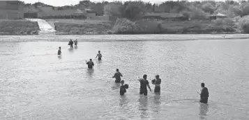  ??  ?? Would- be immigrants wade across the Rio Grande at the U. S.- Mexico border in Roma, Texas. U. S. Border Patrol agents intercepte­d the group on the Texas side.