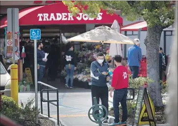  ?? Francine Orr Los Angeles Times ?? A MAN wearing a face mask accepts hand sanitizer before entering a Trader Joe’s in South Pasadena last month. Federal officials maintain that healthy people do not need to wear masks in most circumstan­ces.