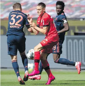  ??  ?? Florian Wirtz of Leverkusen is challenged by Bayern’s Alphonso Davies, right, and Joshua Kimmich during their Bundesliga match in Leverkusen, Germany, on Saturday.