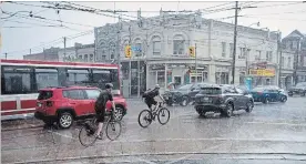  ?? TIJANA MARTIN THE CANADIAN PRESS ?? Cyclists make their way through Toronto during a thundersto­rm Wednesday. Hydro One said about 47,000 customers were without power, many due to storm-related outages.