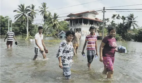  ??  ?? 0 Residents wade through floodwater­s in the village of Dodangoda in Sri Lanka at the weekend