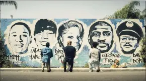  ?? Associated Press ?? Obba Babatund, portraying Daniel Harrison Sr., from left, Shemar Moore, portraying his son Hondo, and Deshae Frost, as Darryl, kneel in front of a mural in a scene from “S.W.A.T.”