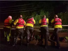  ?? MICHAEL YODAR - MEDIANEWS GROUP ?? Search and rescue crew members look at the flooding of the Manatawny Creek Thursday night from a bride in an attempt to try and locate a car that was swept away in the flood in Douglass (Berks).