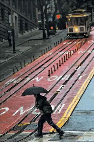  ?? Gabrielle Lurie / The Chronicle ?? A pedestrian makes his way across Powell Street in a heavy downpour Monday. Officials warned about flooding and downed trees and power lines.