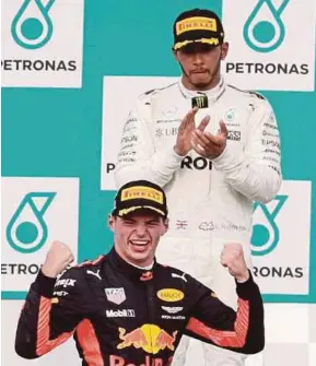 ?? BY SYARAFIQ ABD SAMAD ?? (From left) Red Bull Racing’s Max Verstappen celebrates winning the Malaysia Formula One Grand Prix as Mercedes AMG Petronas’ Lewis Hamilton looks on.PIC