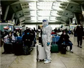  ?? NOEL CELIS/AFP VIA GETTY IMAGES ?? A passenger wore full-body protective gear at a train station in Beijing on Wednesday.