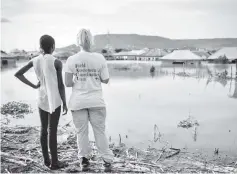  ??  ?? Photo shows Natalie Edlen (right) of the IFRC Field Assessment Coordinati­onTeam (FACT) team standing with a woman near a flooded area at the Favour Gadumo internally displaced people (IDP) camp in Kogi State, central Nigeria. — AFP photo