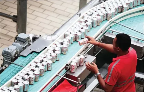  ?? HONG MENEA ?? A Khmer Beverages employee sorts Cambodia beer cans on an assembly line yesterday at the company’s factory near Phnom Penh.