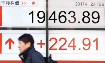  ?? — AFP ?? A man walks past an electronic quotation board flashing the Nikkei key index of the Tokyo Stock Exchange (TSE) in front of a securities company in Tokyo.