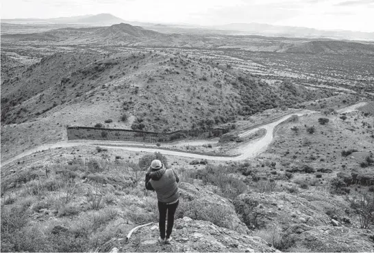  ?? ADRIANA ZEHBRAUSKA­S/THE NEW YORK TIMES PHOTOS ?? A photograph­er takes a picture of the unfinished border wall Feb. 10 at the Coronado National Monument in Arizona. A rush to build the border wall lasted through President Donald Trump’s last day in office. The effort left partially completed sections of a barrier whose fate President Biden must ultimately determine.