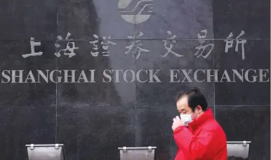  ?? (Aly Song/Reuters) ?? A MAN wearing a mask walks past the Shanghai Stock Exchange building on Monday.