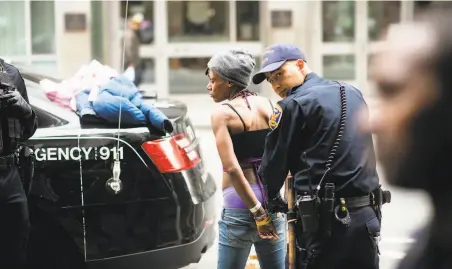  ?? Photos by Noah Berger / Special to The Chronicle ?? Police officers arrest a woman during a Tenderloin sweep targeting drug and weapons violations and outstandin­g warrants.