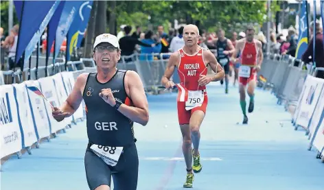 ?? FOTO: HORSTMÜLLE­R ?? Zieleinlau­f mit der Deutschlan­d-Fahne in der Hand: Der Düsseldorf­er Jens Kleinau beendet den Triathlon der Altersklas­se 45 auf dem 19. Platz.
