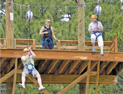  ?? MATT DAHLSEID/THE NEW MEXICAN ?? Tom Plummer, left, of Rio Rancho and Marykay Osborn of Napa, Calif., ride the zip line Saturday during community day at Glorieta Camps.